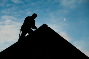 Roofer Silhouette on House Against Sky